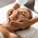 Portrait of relaxed middle aged woman having facial massage in spa center, beautiful mature lady enjoying double chin treatment at modern beauty studio, getting skin lifting care, closeup shot